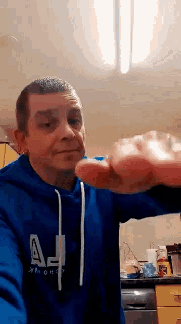 a man wearing a blue aj hoodie holds his hand up