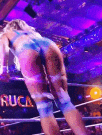 a woman is standing in a wrestling ring with a sign that says rucca on it .