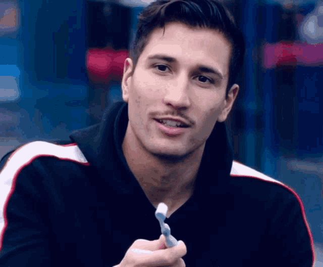 a man with a mustache is smiling and holding a toothbrush