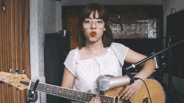 a woman playing a guitar with a microphone attached to it
