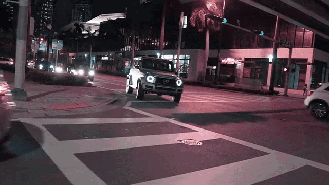 a mercedes is driving down a street at night with a purple light