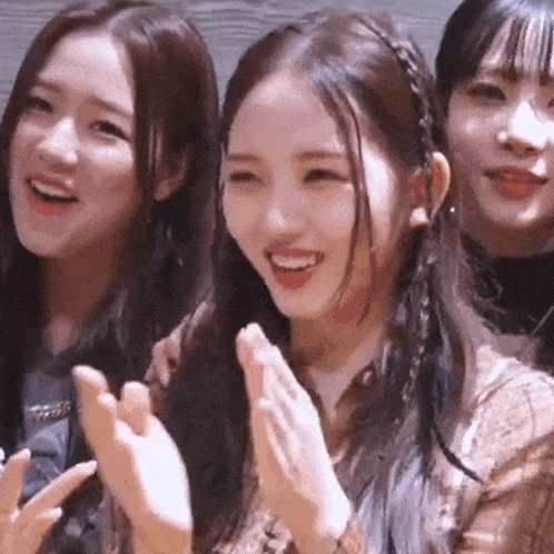 a group of young women are standing next to each other and clapping .