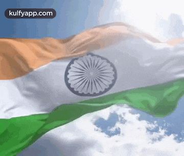 the indian flag is waving in the wind against a blue sky with clouds .