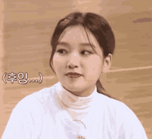 a woman in a white shirt and turtleneck is looking at the camera .