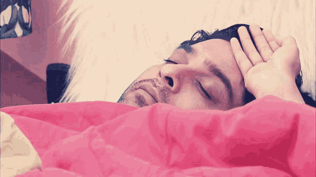 a man laying on a bed with his hand on his head