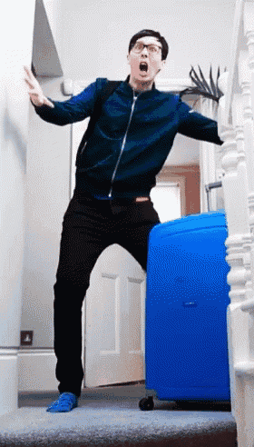 a man in a blue jacket is standing on a set of stairs with a blue suitcase