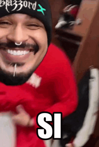 a man wearing a red shirt and a black beanie with the word blizzard on it