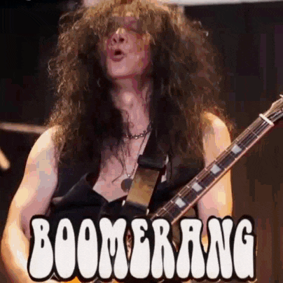 a man with long curly hair is playing a guitar in front of a boomerang sign .