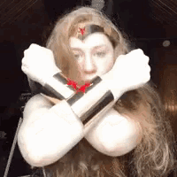 a woman in a wonder woman costume is crossing her arms in front of her face .