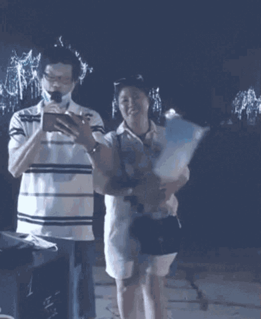 a man wearing a mask looks at his phone while standing next to a woman holding cotton candy