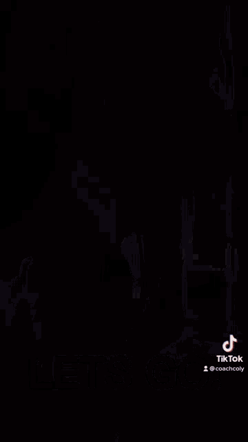 a man wearing headphones is standing in front of a black refrigerator with stickers on it