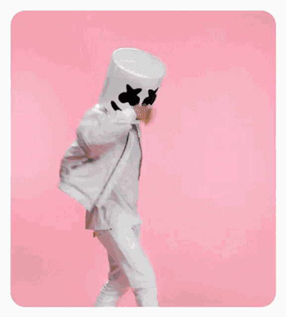 a person in a marshmallow costume is standing on a pink background .