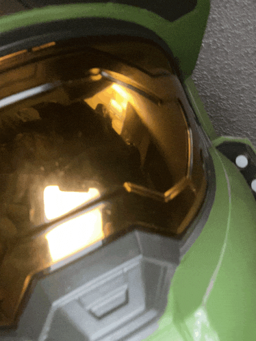 a close up of a green halo helmet with a yellow light coming out of it