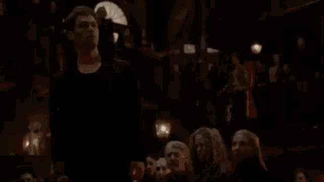 a man in a black shirt is standing in front of a crowd