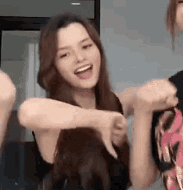 a woman with long hair is dancing with two other women in a room and smiling .