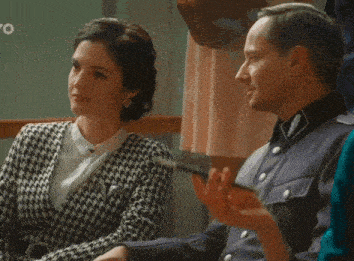 a man and a woman are sitting next to each other in a room . the man is wearing a uniform .
