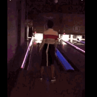 a person is walking down a bowling alley with a sign that says ' bb ' on it