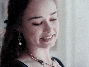 a woman wearing a pearl necklace and earrings is smiling .