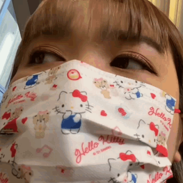 a woman wearing a hello kitty mask looks at the camera