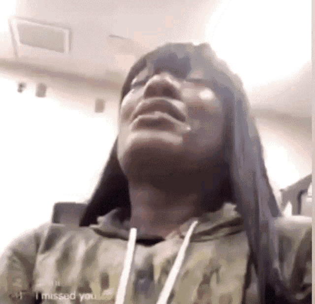 a woman is crying while wearing a camo hoodie and a hoodie that says i missed you .