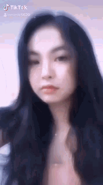 a close up of a woman 's face with long black hair looking at the camera .