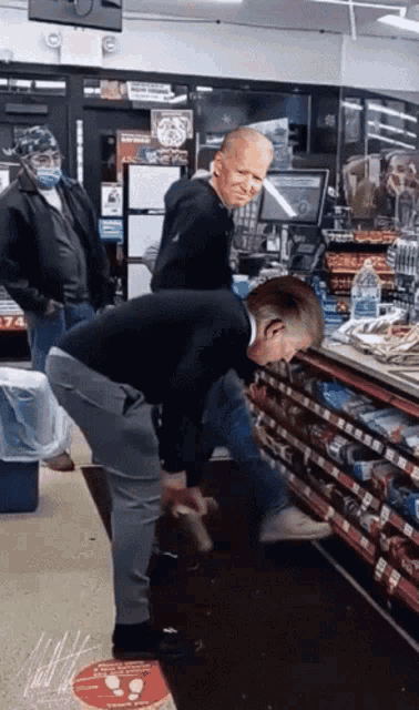 a man squatting down in front of a shelf in a store with a sticker on the floor that says " no touching "