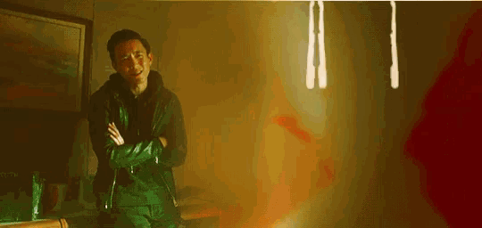a man with his arms crossed is standing in a dark room