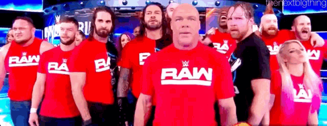 a group of wrestlers are standing next to each other in red shirts .