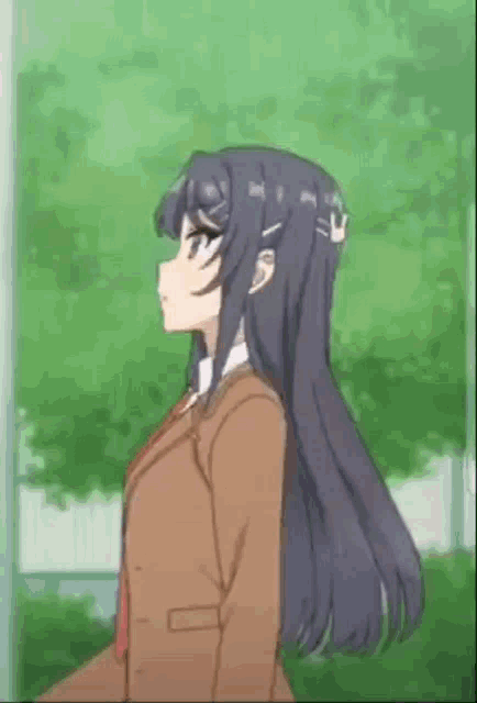 a girl with long hair is standing in front of a tree in a park .