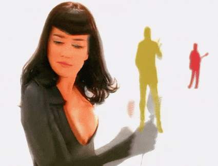 a woman with a plunging neckline is standing in front of a silhouette of a man playing a guitar