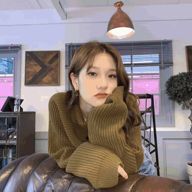 a woman wearing a green sweater is sitting on a couch