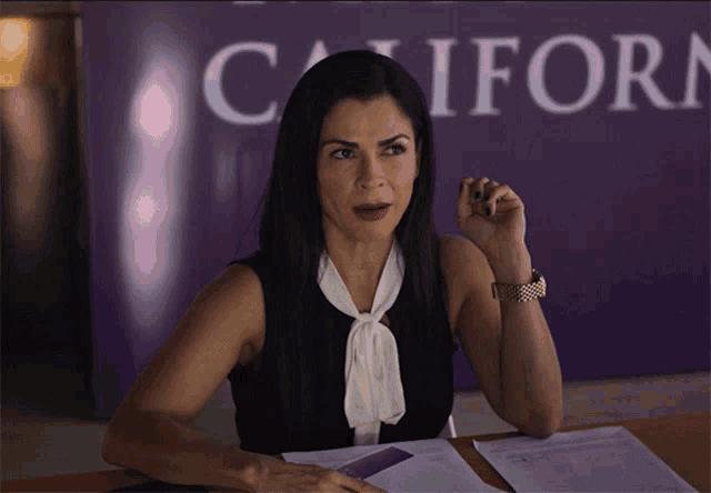 a woman sits at a desk in front of a california sign