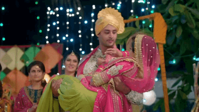 a man is carrying a woman in a pink and green dress