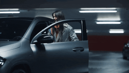 a woman is getting out of a car in a dark parking garage