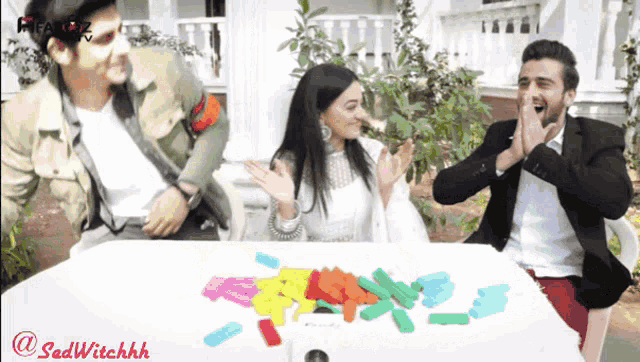 two men and a woman are sitting at a table with a bunch of colorful sticky notes on it