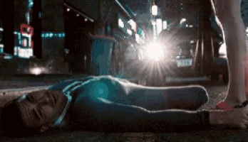 a man is laying on the ground in front of a street light that says taxi on it
