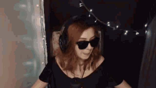 a woman wearing headphones and sunglasses is sitting in a chair in front of a microphone .