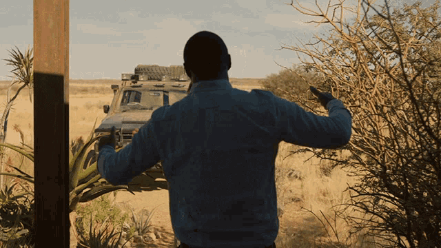 a man in a blue shirt is standing in front of a vehicle