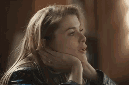a woman in a leather jacket is sitting at a table with her hand on her chin .