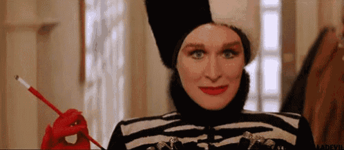 a woman wearing a zebra print jacket and a fur hat is holding a cigarette in her hand .