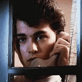 a man is talking on a phone while looking out of a window