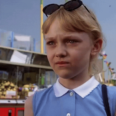 a little girl wearing sunglasses and a blue shirt looks sad