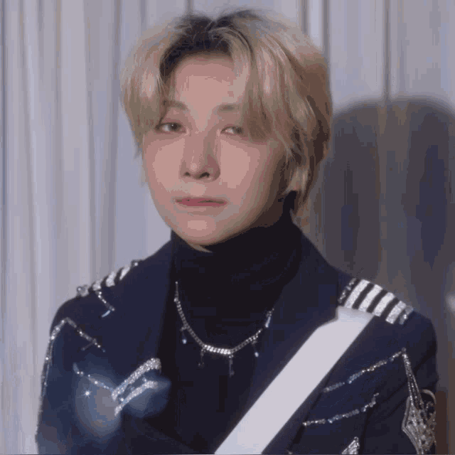 a close up of a person wearing a turtleneck and a necklace