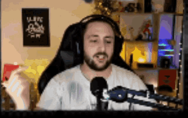 a man wearing headphones and a white shirt is sitting in front of a microphone in a room
