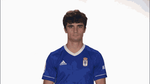 a man wearing a blue adidas shirt holds his arms up