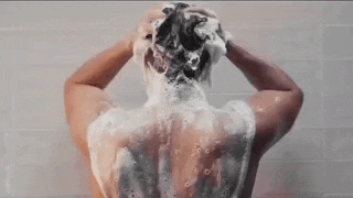 a man is taking a shower and washing his hair in the shower .