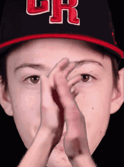a young boy wearing a cr hat covering his face