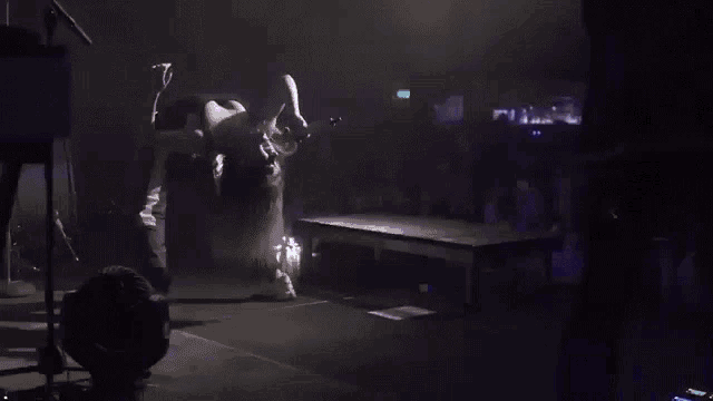a woman is doing a handstand on a stage with purple lights behind her