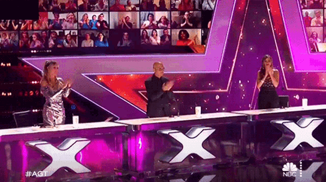 a man and two women are sitting at a table with a large x on it
