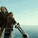 a couple of people are standing on the deck of a boat in the ocean looking up at the sky .